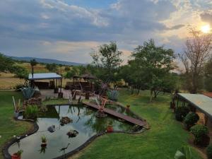 a garden with a pond with a bridge and trees at Nyani Lodge Dinokeng in Pretoria