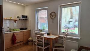 a kitchen with a table and chairs and two windows at Green cottage Besenova in Bešeňová