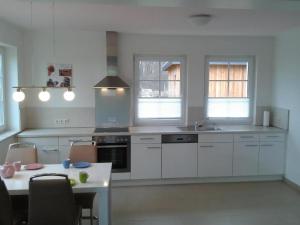 a kitchen with white cabinets and a table with chairs at Ferienwohnung 4 in Dassow