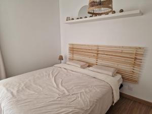 Un dormitorio con una cama blanca con cabecero de madera. en T3 Duplex - Centre-ville, en Saint-Pourçain-sur-Sioule 2 fotos más