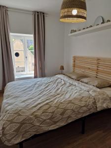 Una cama en un dormitorio con una ventana grande. en T3 Duplex - Centre-ville, en Saint-Pourçain-sur-Sioule
