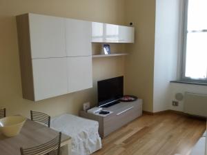 cocina con armarios blancos, mesa y TV en Appartamento Stefania, en Milán