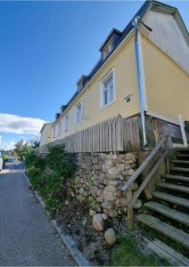 a yellow house with a stone wall and stairs at Pispalan Helmi - Koti Näköalalla in Tampere +6 photos
