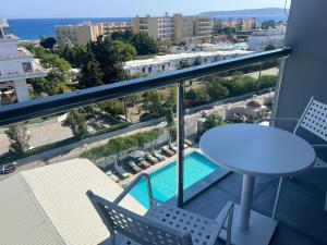 a balcony with a table and chairs and a pool at OSIRIS HOTEL APARTMENTS and STUDIOS in Ialyssos