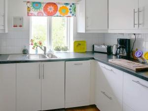 a kitchen with white cabinets and a sink and a window at 4 star holiday home in Laholm in Laholm +16 photos