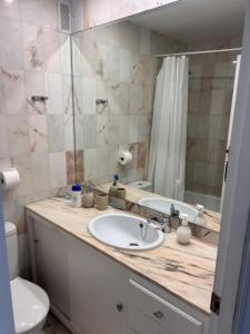 Un baño con lavabo, inodoro y espejo. en Primera linea de playa, en Cabopino 11 fotos más