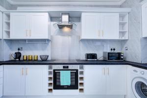 a kitchen with white cabinets and a washer and dryer at London Baker Street Apartment in London +18 photos