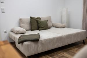 a white couch with green pillows in a living room at Ferienwohnung Fränkische Auszeit in Wolframs-Eschenbach