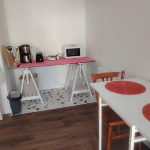 Una cocina con un escritorio rosa con microondas. en PETIT STUDIO DAnS UN JARDIN, en Pornic
