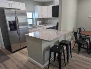 a kitchen with a stainless steel refrigerator and bar stools at The Calico Cottage in Lewis Center