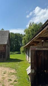 an old barn sitting next to a grass field at Folwark Hańcza in Wigry