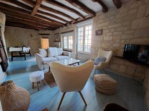 a living room with a couch and chairs and a tv at Le chant du troglodyte in Saumur