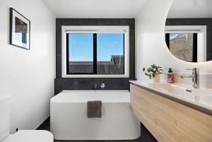 a white bathroom with a tub and a sink at Alpenglow Lodge with steam sauna in Queenstown +21 photos