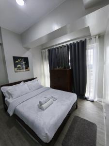 a bedroom with a bed with white sheets and a window at RQ Stays! at Milan Residenze Fairview in Manila +21 photos