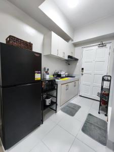 a kitchen with a black refrigerator and white cabinets at RQ Stays! at Milan Residenze Fairview in Manila