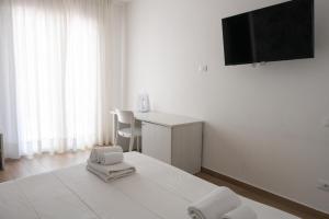 a white room with a bed with a desk and a television at Bed and Breakfast Al Portanova in Reggio Calabria
