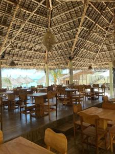 a restaurant with tables and chairs and a large ceiling at Amour Beach Villas in Paje