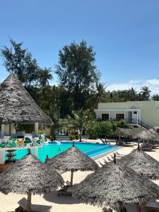 a swimming pool with straw umbrellas and a resort at Amour Beach Villas in Paje