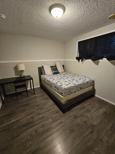 Un dormitorio con una cama y una mesa con una lámpara. en Basement Appartment, en Edmonton