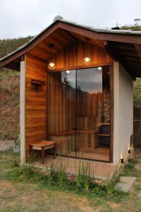 Una pequeña cabaña con una gran ventana de cristal y un banco. en Refugio Vale da Mantiqueira Visconde de Mauá, en Visconde De Maua 11 fotos más