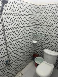 a bathroom with a white toilet and black and white tiles at Studio meublé Saint Louis Sénégal in Saint-Louis