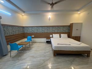 a bedroom with a bed and two blue chairs at Vainavi Residency in Tirupati