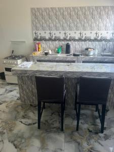 a kitchen with two chairs in front of a counter at Studio meublé Saint Louis Sénégal in Saint-Louis