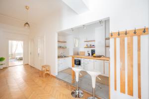 a kitchen with white cabinets and a wooden floor at The City Gem in Bratislava