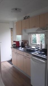 a kitchen with a stove top oven next to a window at Jachtslot Chalet J8 in Doornspijk