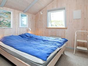 a bedroom with a bed with a blue blanket on it at 4 star holiday home in Henne in Henne Strand