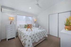 a white bedroom with a bed and a window at Popular Central Coastal Apartment in Maroochydore