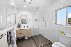 a white bathroom with a shower and a sink at Popular Central Coastal Apartment in Maroochydore