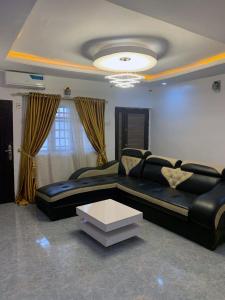 a living room with a black couch and a table at Cee&Tee at AKOBO 1Bedroom or 2Bedrooms -247 Electricity-Solar Inverter AC in Bedrooms in Ibadan