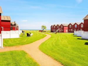 un chemin de terre devant un champ avec des maisons rouges dans l'établissement Seaside Retreat in oster Hurup-By Traum, à Hadsund
