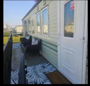 a porch with a white door and a couch at Julie and Shaun's in Ingoldmells