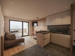 a kitchen with white cabinets and a table with a couch at Oachner Living in Feldthurns +13 photos