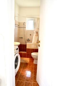a bathroom with a toilet a sink and a washing machine at View & Chill Syros in Vari +13 photos
