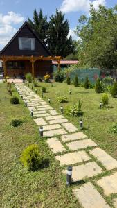 a stone pathway in a garden with a house in the background at Căsuța cu tihnă in Porumbacu de Sus