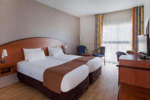 a hotel room with a large bed and a television at Grand Hotel in Dax