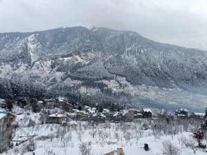 a snow covered mountain with a town in the foreground at Hotel Old Manali ,Monthly Room with Kitchen Only Rs 18000 in Manāli
