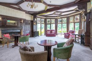 a living room with a fireplace and tables and chairs at Northop Hall Country House Hotel in Mold