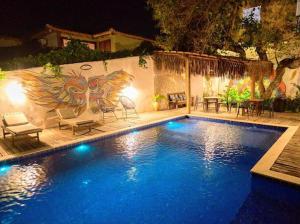 a swimming pool at night with a painting on the wall at Recanto do Villa 3 in Trancoso