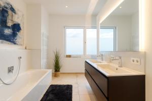 a white bathroom with a tub and a sink at Penthouse Vogelnest 130 qm - BBQ - Dachterrasse in Passau +20 photos