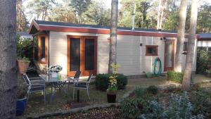 a small house with a table and chairs in a yard at Jachtslot Chalet J8 in Doornspijk
