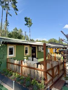 a green house with a wooden fence at Ferienhaus am See in Staupitz