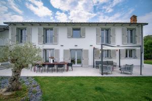 a white house with a table and chairs at Villa Immersa Tra Le Vigne Con Piscina Riscaldata in Castiglione Tinella