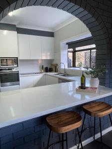 Una cocina con una encimera blanca y dos taburetes. en The Kookaburra house in Moss Vale 5Br Pet friendly, en Moss Vale