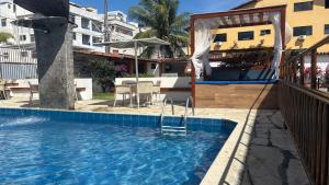 a pool with a table and chairs in a building at Pousada Mar E Mata in Guarapari