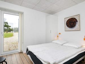 a white bedroom with a bed and a window at 5 star holiday home in Ringkøbing in Ringkøbing