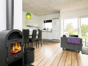 a living room with a fireplace and a kitchen at 5 star holiday home in Ringkøbing in Ringkøbing